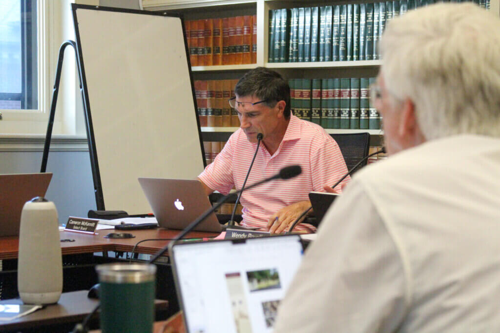 Select Board members Cameron McKennitt, left, and Dean Banfield, right, review trail marker plans on their laptops. Photo: Dakota Antelman/The Acton Bridge