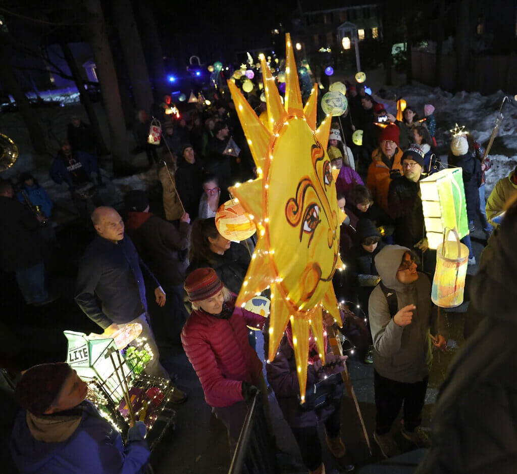 Polly Vanasse of Acton  carries an illuminated sun lantern, the work of Acton artist Deb Richardson, as the parade files into the Scout House. 
