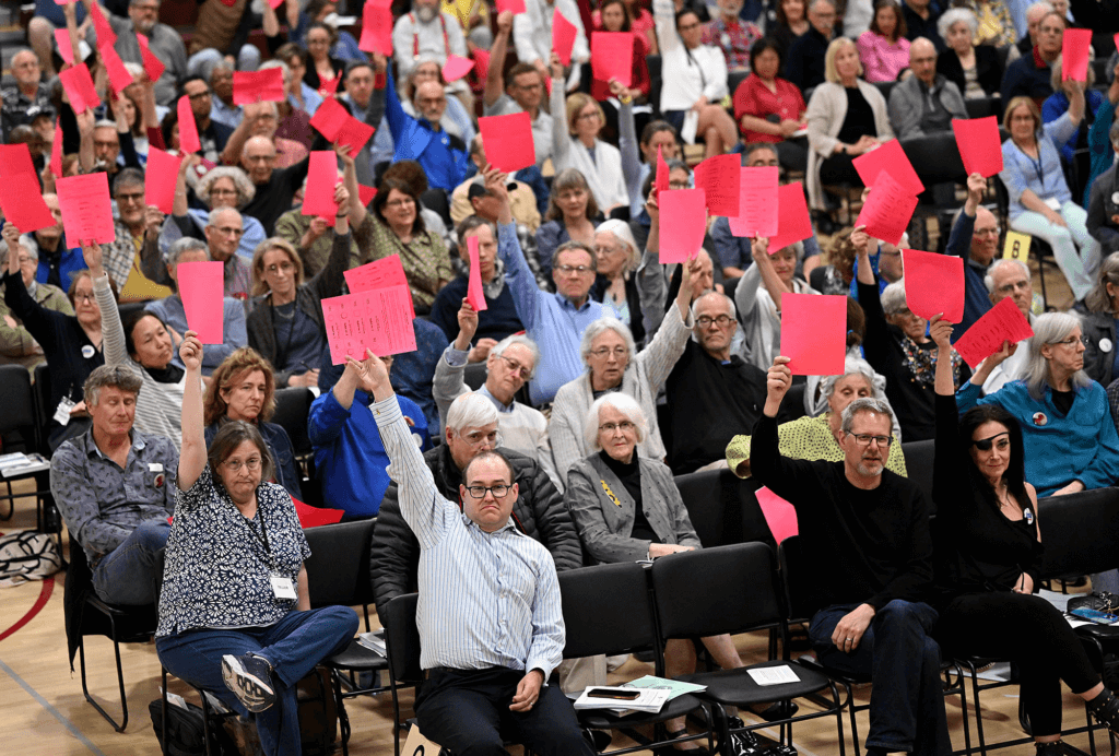 Acton residents raise their paper slips to vote in the traditional manner. on the Finance Committee’s amendment to the Acton-Carlisle Regional School District budget. Photo by Ken McGagh for The Acton Bridge