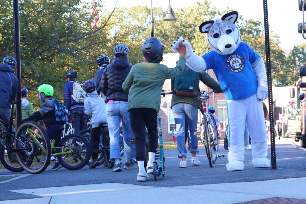 Henry the Husky high-fives students as they arrive at Thoreau Elementary. Photo: Trace Salzbrenner/The Acton Bridge