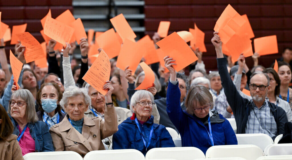 Town Meeting-goers hold up their orange paper ballots to vote against an amendment to the motion on the use of clickers during Town Meeting at Acton-Carlisle High School on Monday, June 2, 2025. Photo: Ken McGagh/The Acton Bridge
