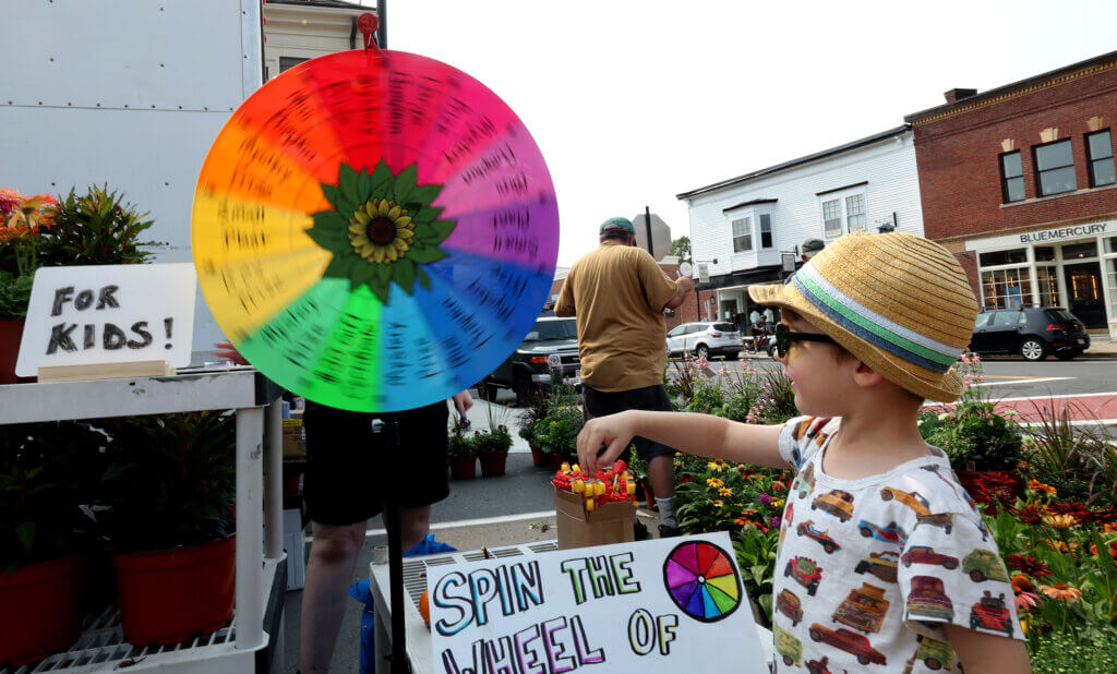 After answering a trivia question, Ellis Way, 4, of Acton, spins the Colonial Gardens “Wheel of Horticulture” to learn his prize. The wheel is a new addition to the yearly celebration of Acton farming.  Ken McGagh/The Acton Bridge 
