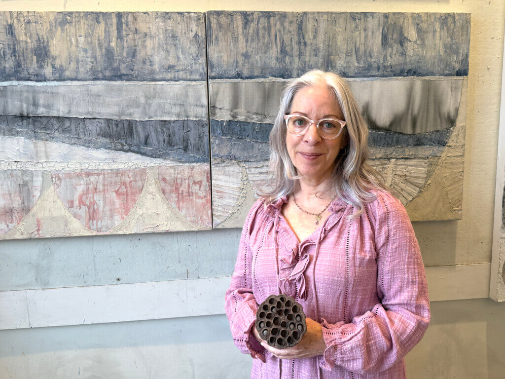 Jill Goldman-Callahan, in her studio, holds a lotus pod, one of nature’s elements that inspires her. Photo: Laurie O’Neill/The Acton Bridge