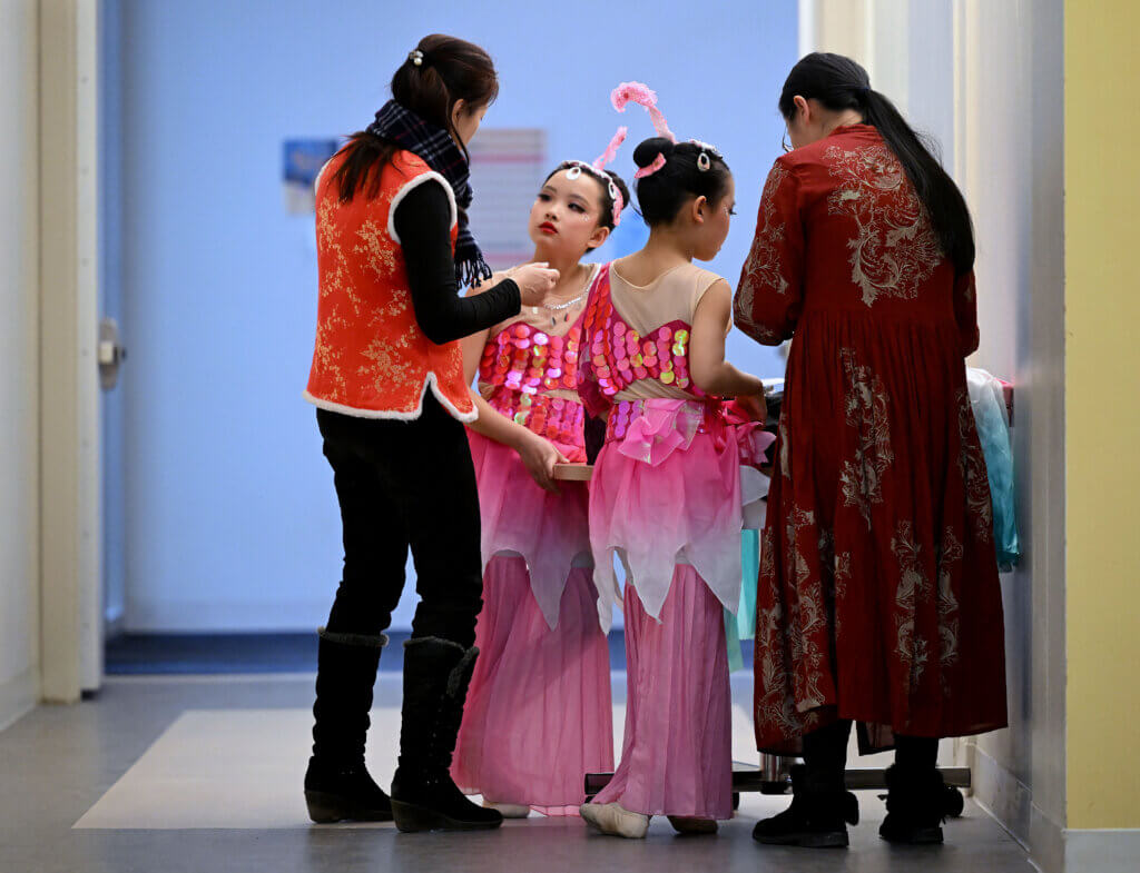 Amelia Qin and Miranda Luo, both 9 and from Carlisle, finish getting makeup before performing their “Joyful Waves Fan Dance.”