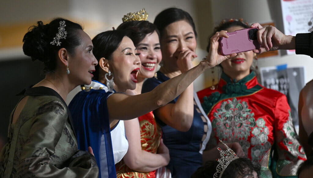 Dancers from the Yuanqi Ladies Team check out a selfie of their troupe after performing.