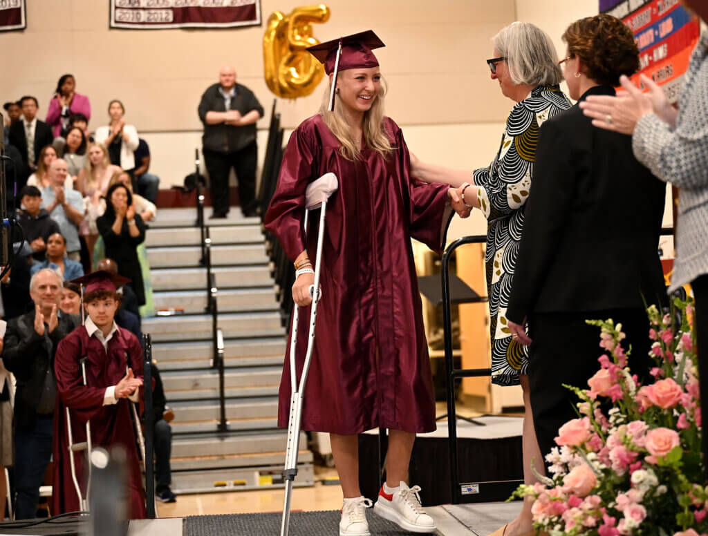 Senior Lauren Costa, the lone survivor of a Florida car crash that took the lives of three classmates on April 21, walks on stage to accept her diploma during graduation exercises on Saturday, May 31, 2025. Ken McGagh/The Acton Bridge