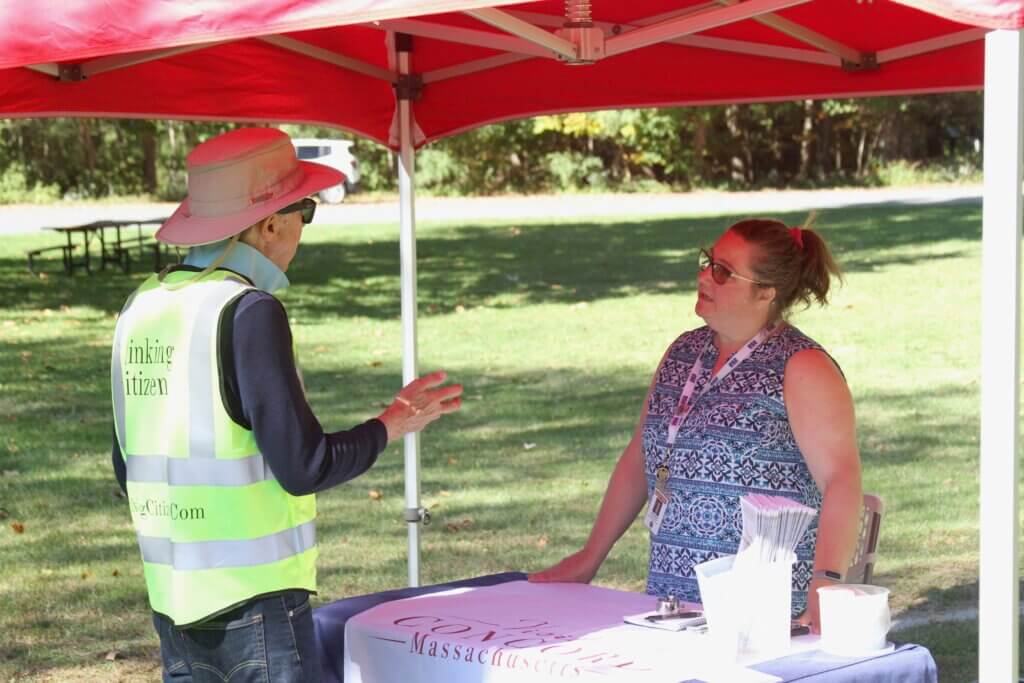 Town Tourism Manager Beth Williams speaks with John Muresianu, a North Bridge regular who often sings a multilingual repertoire of songs for National Park visitors. Photo: Dakota Antelman/The Acton Bridge