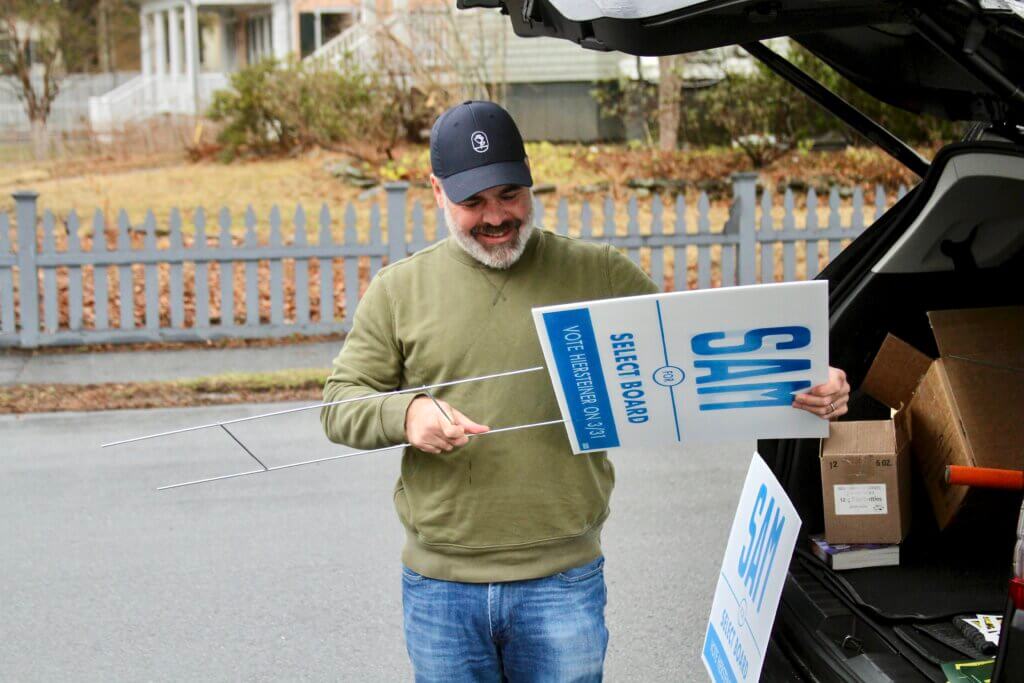 Select Board candidate Sam Hiersteiner set up campaign signs near the Hunt Recreation Center polling place this morning as voting got underway. Photo: Dakota Antelman/The Acton Bridge