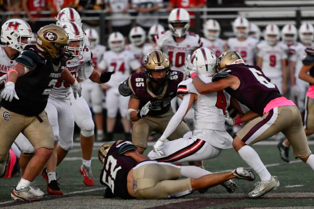 The Patriots’ Aidan Bayes (6), Liam Denis (56), and Charlie Whitmore (65) combine on a tackle. Photo by Cris Van Dyke