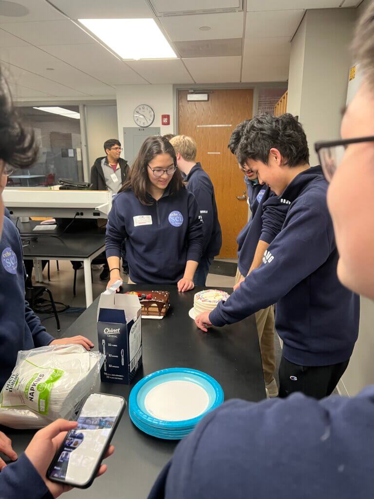 Gabrielle Whidden and Shaunit Bajoria offer guidance as Evan Wang cuts his birthday cake. Photo by Lauren Wright
