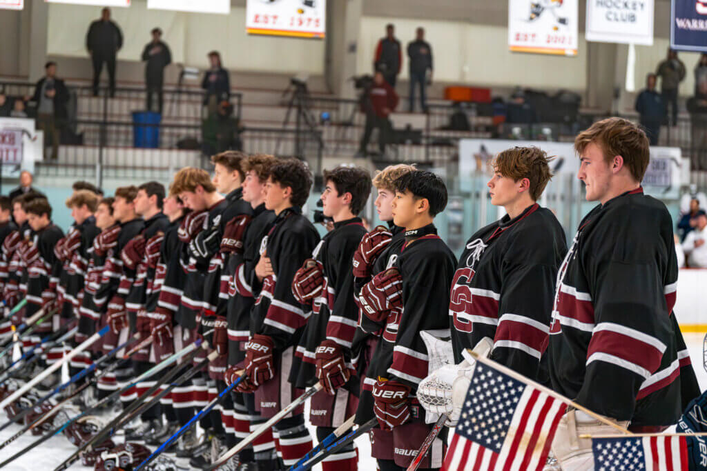 The Acton-Carlisle men's hockey team lines up for the national anthem at the annual Warriors 4 Warriors event on December 13 at NESC. Photo by Aidan Moroney