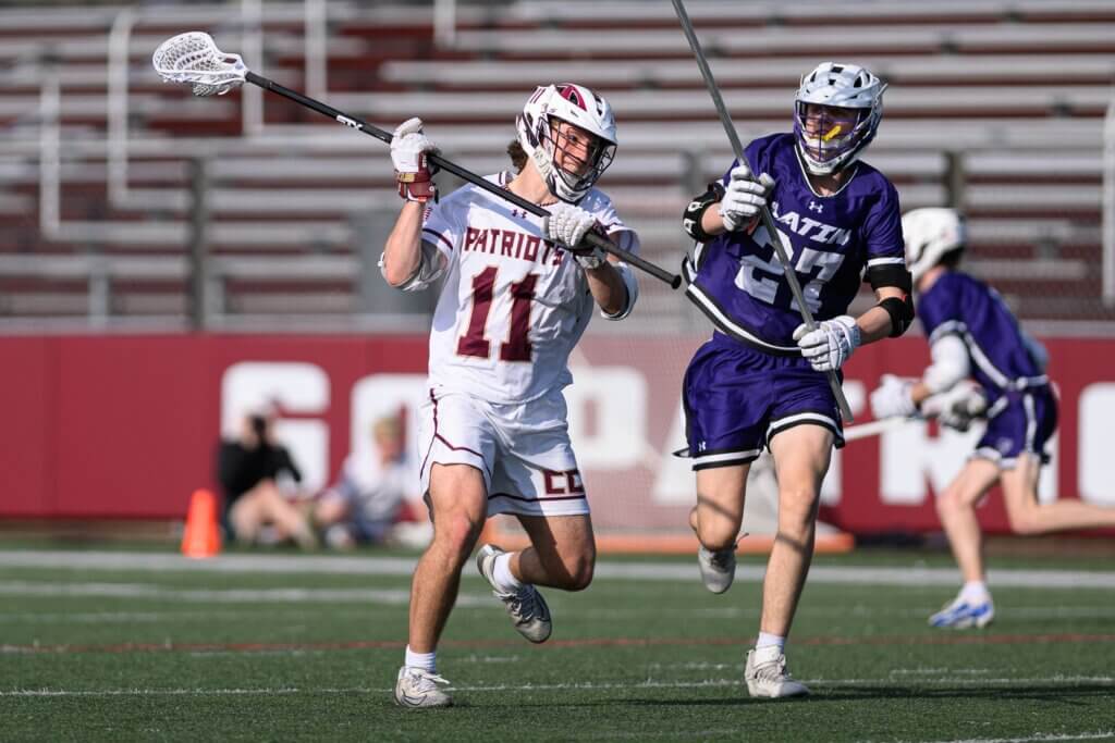 Patriots defenseman Aidan Bayes (No. 11) moves the ball upfield against Boston Latin on April 14. Photo by Jon Straggas