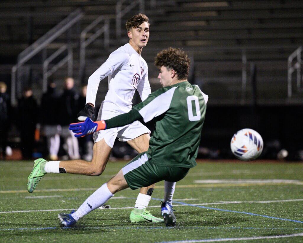 The Patriots’ Max Hepworth outmaneuvers St. John’s Prep goalkeeper Matthew Droggitis for a score in the MIAA semifinal match on November 17. Photo by Jon Straggas