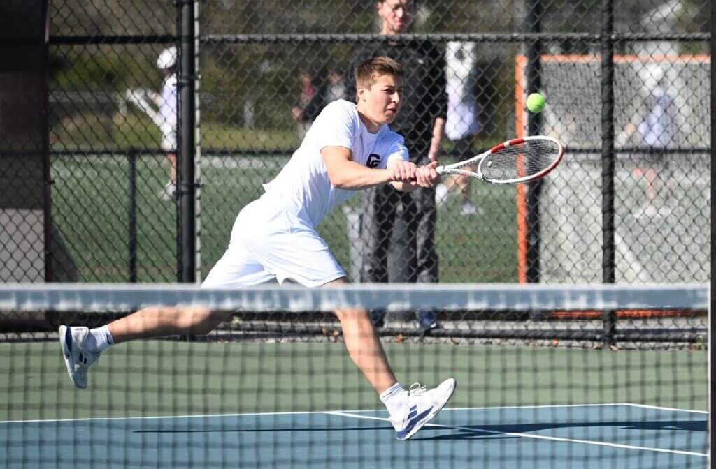 Acton-Carlisle’s Charlie Whitmore reaches for a backhand return on May 1 against Waltham. Photo by Alexis Guinebertiere