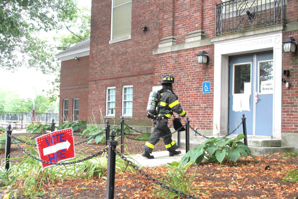 A firefighter enters the Hunt Recreation Center to investigate an ultimately unfounded report of a gas leak during election day voting. Photo: Dakota Antelman/The Acton Bridge