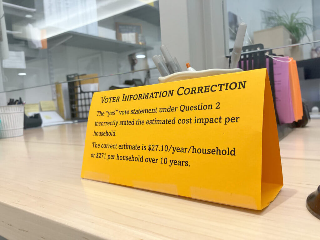 A paper sign advertises corrected information from a townwide voter information mailer outside the Town Clerk’s Office. Photo: Dakota Antelman/The Acton Bridge