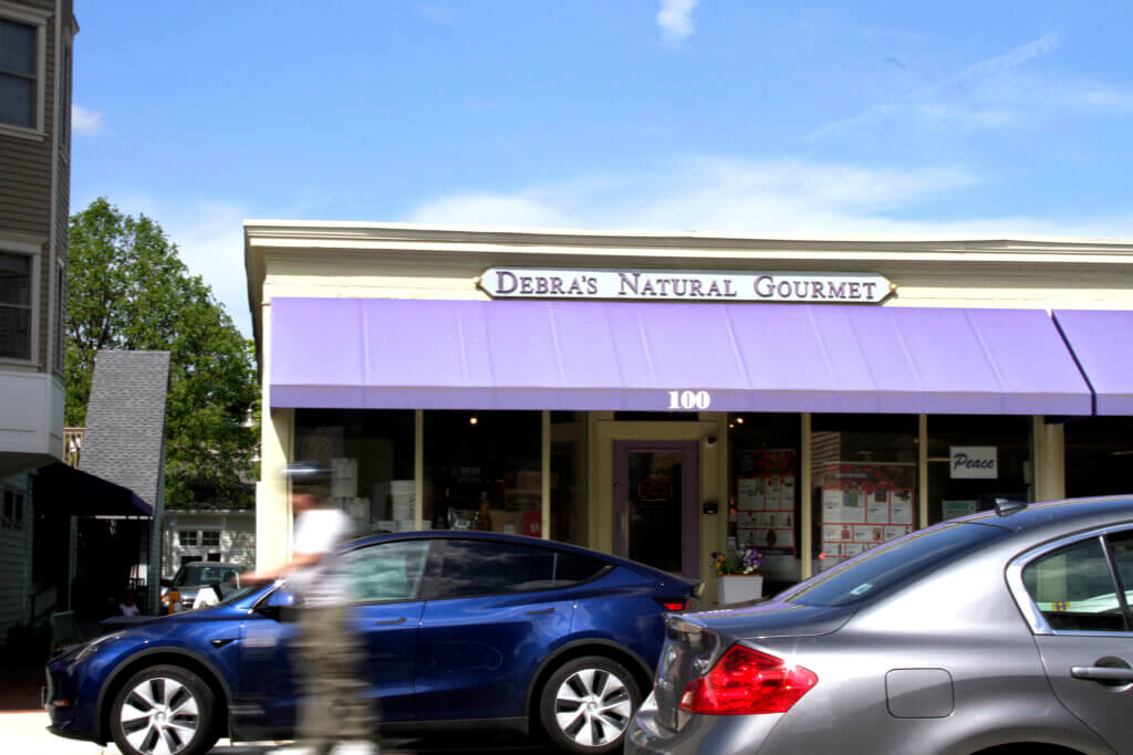 A scooter rider passes Debra’s Natural Gourmet. Photo: Dakota Antelman/The Acton Bridge