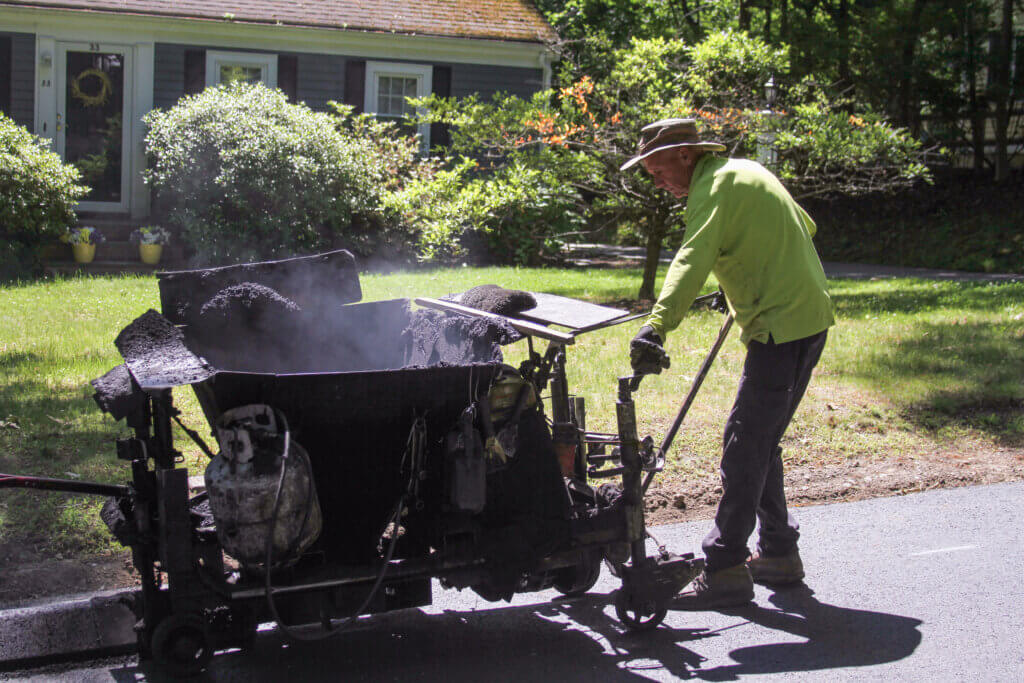 Ken Wyer guides a curbing machine as crews put the finishing touches on an Orchard Road resurfacing effort. Photo: Dakota Antelman/The Acton Bridge