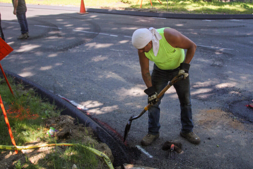 Carlos Orozco shapes a curb with a shovel. Photo: Dakota Antelman/The Acton Bridge