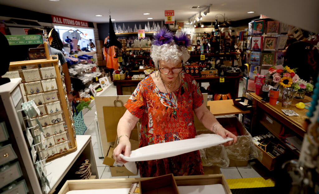 Revolutionary Concortd owner Marie Foley wraps a gift for a customer behind the register of shop in the basemenet at 32 Main Street in Acton Center on Saturday, September 6, 2025 After thirty years in business in Acton, Foley is retiring and closing her electic gift shop. Ken McGagh/The Acton Bridge