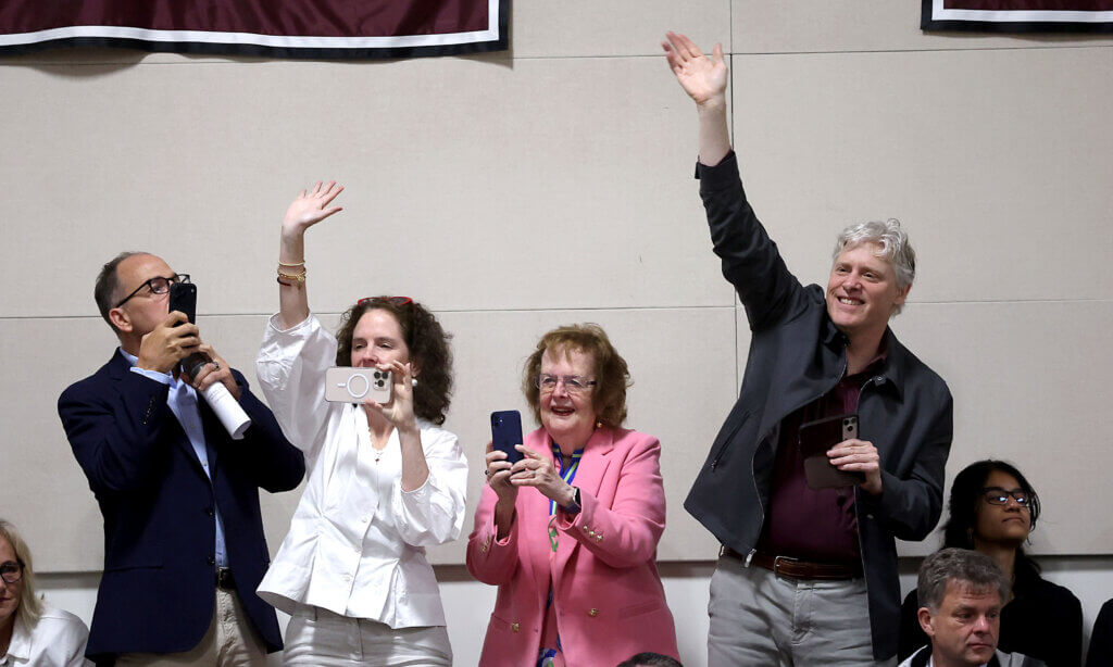 Spectators wave as graduates enter the gymnasium.