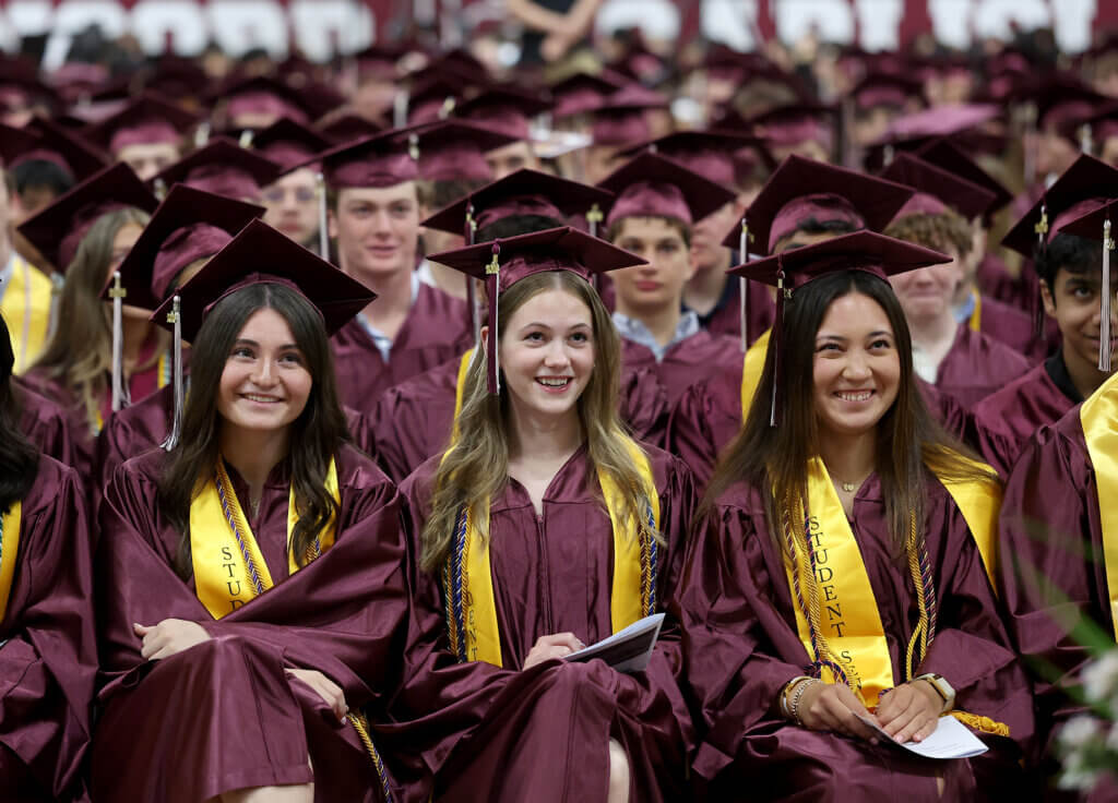 Graduates in the front row smile towards the end of the diploma presentation.