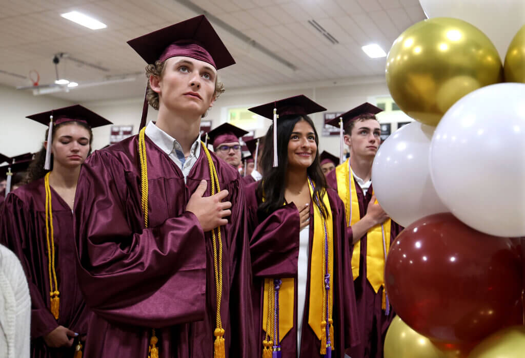 Graham Alderson, left, and fellow graduates stand for the national anthem.