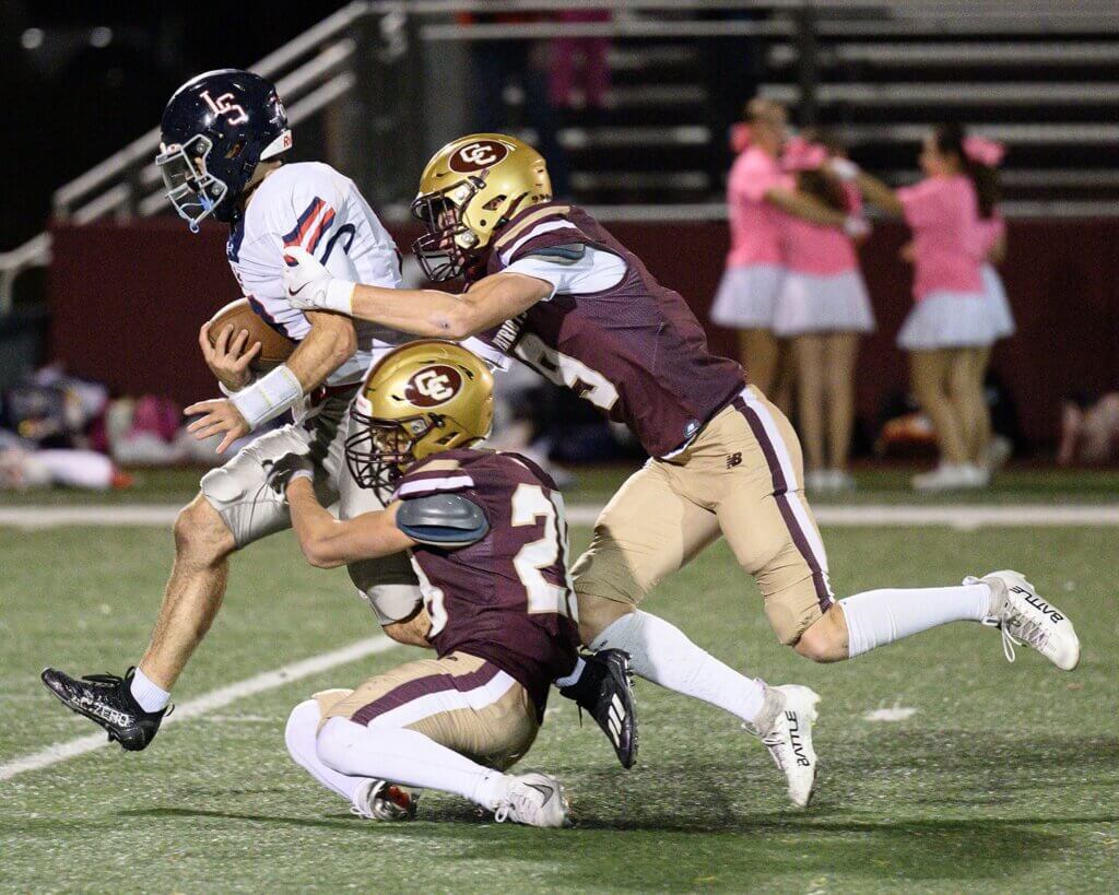 Peter Burke (9) and Henry Johnson (28) chase down Warriors quarterback Matthew Tarantino (No. 9). Photo by Jon Straggas