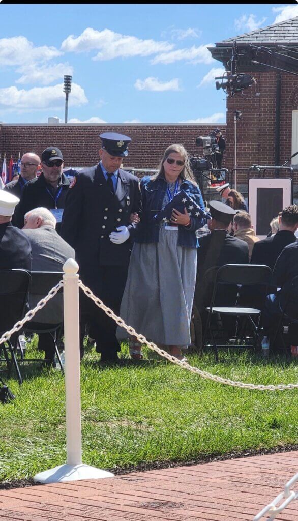 Jeff Lex escorts Capt. Bill Noke’s wife, Rebecca, after she received a folded flag at the National Fallen Firefighters Memorial in Maryland. Photo courtesy Acton Fire Department
