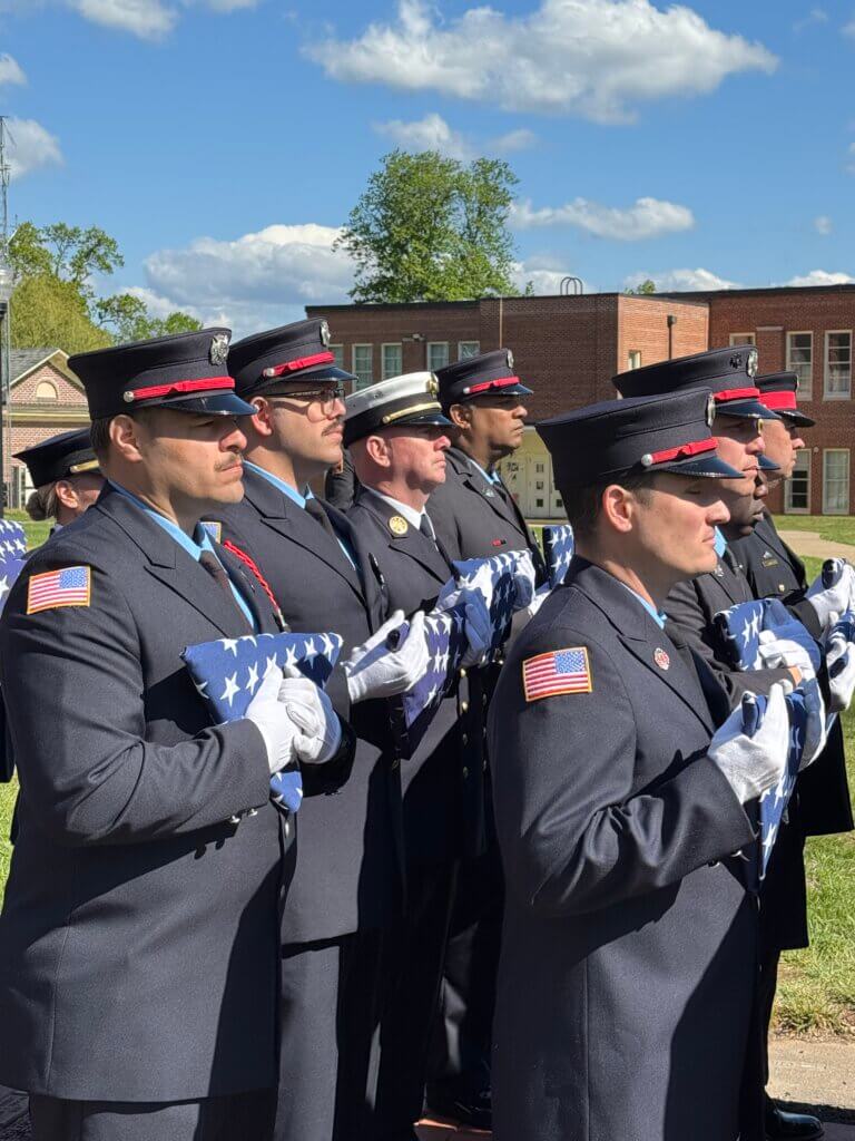 Assistant Fire Chief Sean Murphy, in white hat, holds a flag that was later presented to Capt. Bill Noke’s wife during a ceremony honoring him. Photo courtesy Acton Fire Department