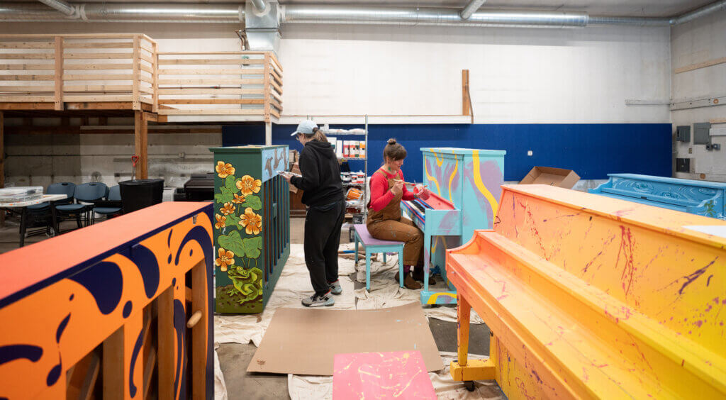 Artists apply detailed layers to the pianos at the conservatory’s CCM2 building in West Acton. Photo by Evan Scales