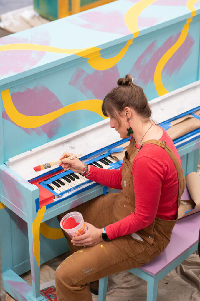 Local artist Jamie Palmer Keating applies colors to her piano titled “Tulip Time.” Photo by Evan Scales