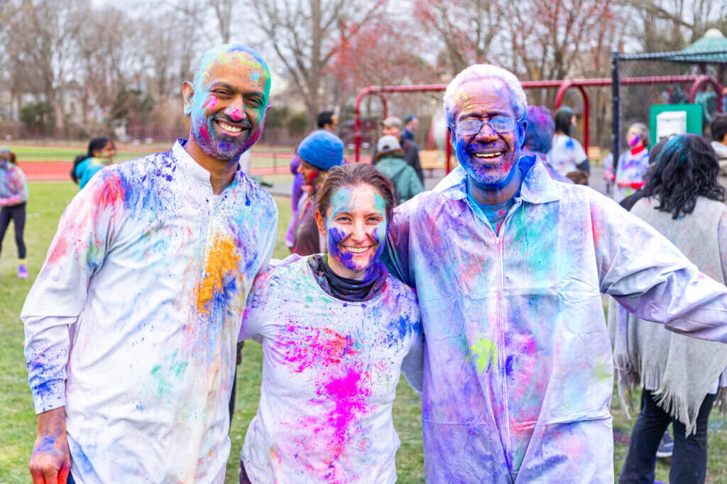 Election 2025 candidates Sandeep Pisharody, Elizabeth Akehurst-Moore, and Michael Williams set aside any political differences to celebrate Holi in the park. Photo: Stephen Beyer/The Acton Bridge