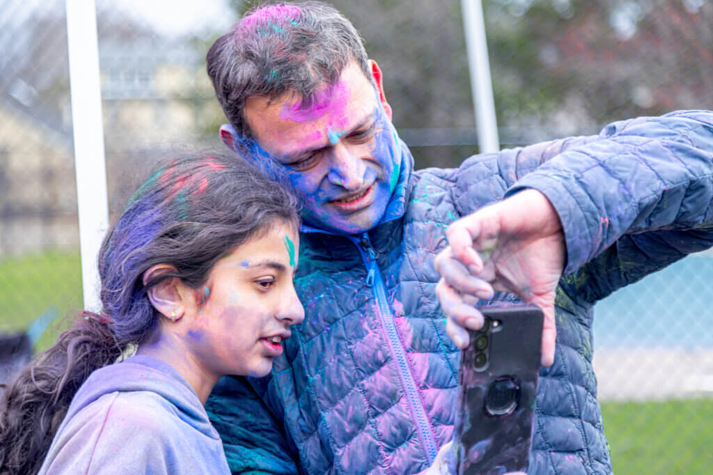 Divya and Dinesh Malev pause for a cameraphone view of the festivities. Photo: Stephen Beyer/The Acton Bridge