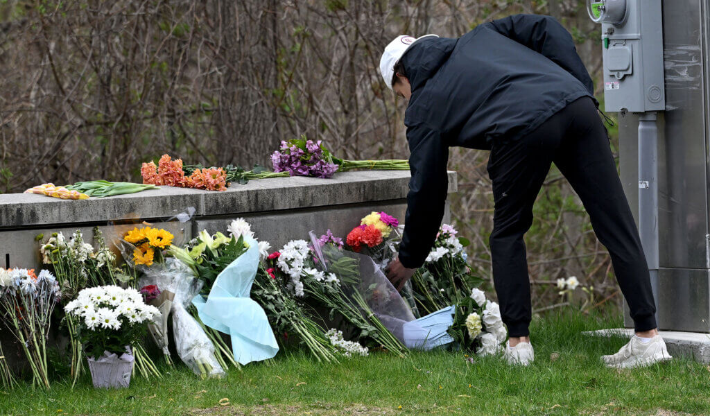 A student places  flowers at the entrance to Acton-Carlisle High School before a community gathering  following the loss of three members of the senior class, and one still critically injured, after a crash on a Florida highway on Sunday, April 27, 2025.  Ken McGagh/The Acton Bridge