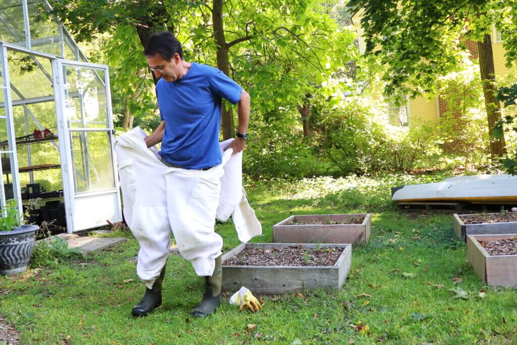 Michael Kielty suits up in his protective gear. The outfit consists of a full bodysuit with attached hood, two layers of gloves, boots, and ankle wraps to keep bees from getting into pant legs. Photo: Trace Salzbrenner/The Acton Bridge