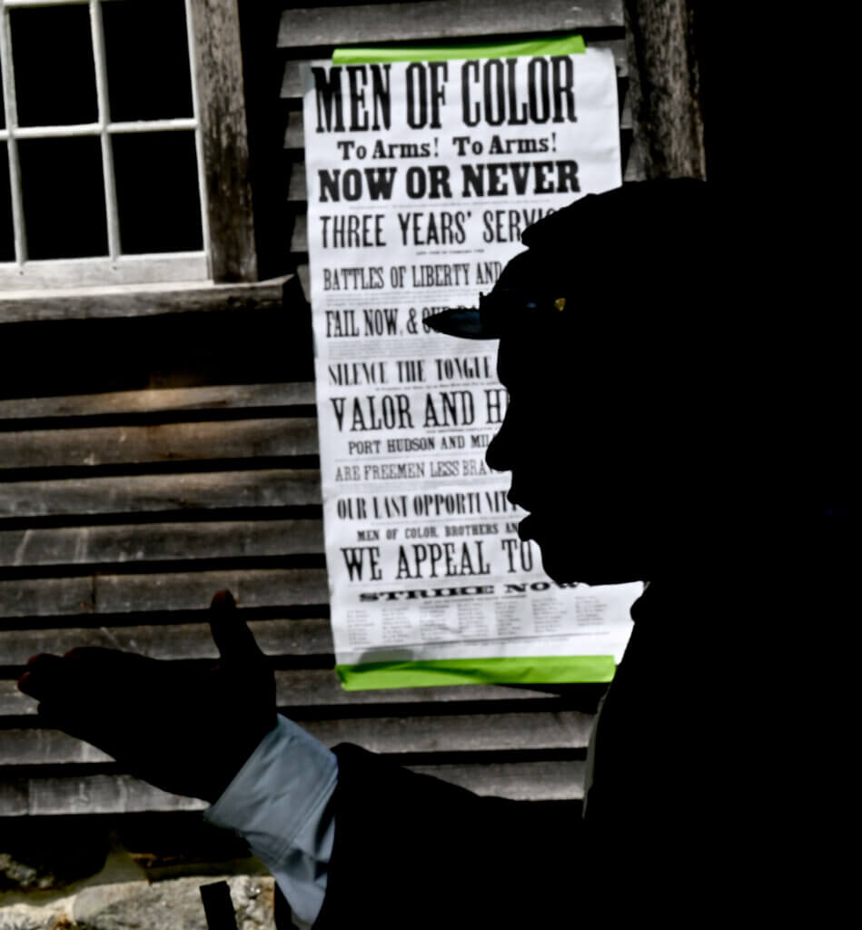 54th Massachusetts Volunteer Infantry Regiment re-enactor Joe Zellner is silhoutted against a proclamation on the Robbins House during a living history Civil War era encampment at the Robbins House in Acton on Saturday, July 26, 2025. The 54th was the first officially recognized Black regiment in the Union army. Ken McGagh/The Acton Bridge