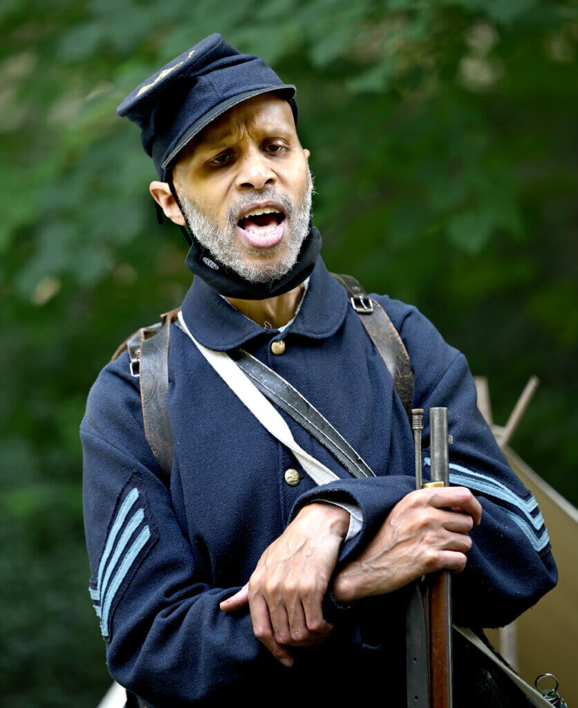 Emmett Bell-Sykes of Boston, portraying Sgt. William H. Carney, the first Black soldier to receive the Medal of Honor, sings during a living history Civil War era encampment with re-enactors of the 54th Massachusetts Volunteer Infantry, the first officially recognized Black regiment in the Union Army, at the Robbins House in Acton on Saturday, July 26, 2025. Ken McGagh/The Acton Bridge