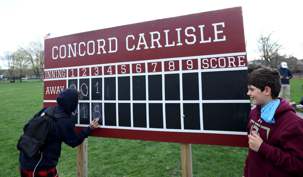 Youngsters update an old-fashioned and rarely used Emerson Field scoreboard with eight CC runs in the bottom of the third inning. The Patriots scored nine runs that inning and routed the Minutemen 15-1. Photo: Ken McGagh/The Acton Bridge