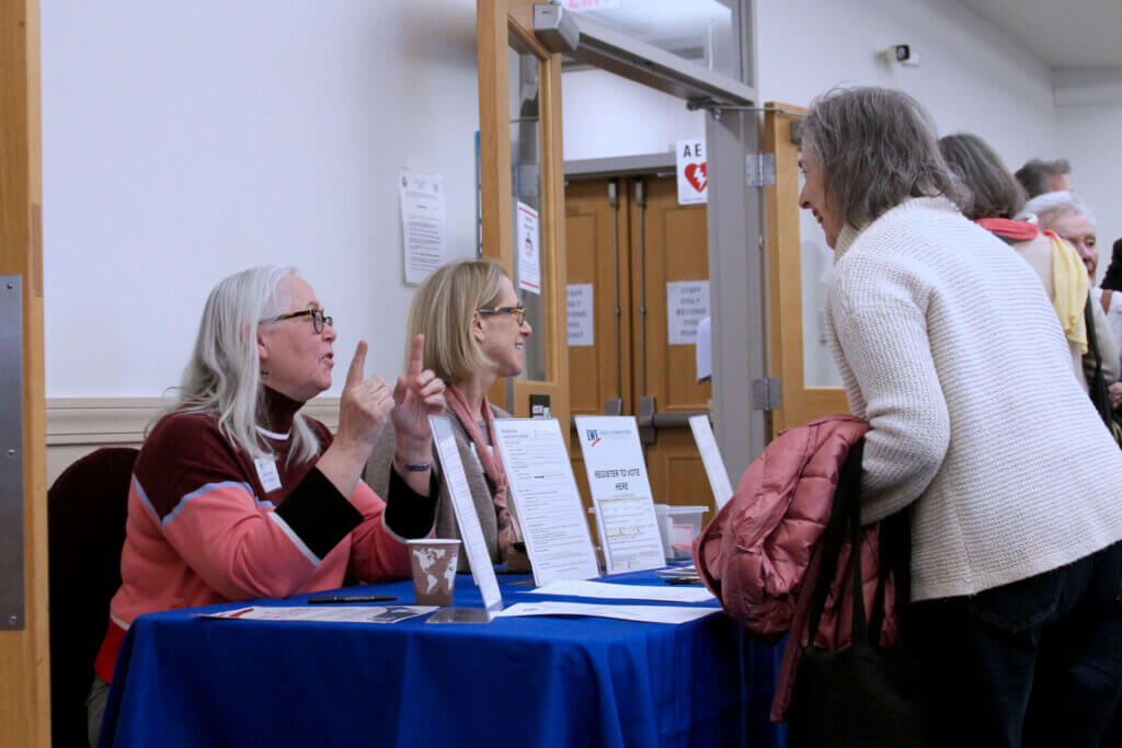 Volunteers staff a League of Women Voters information booth at a March 25 candidate forum. Photo: Dakota Antelman/The Acton Bridge