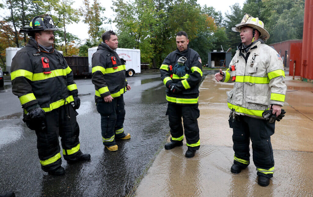 Acton Fire Department Assistant Chief Sean Murphy, right, briefs Acton firefigher Keegan Byrnes, left, Acton Fire Department Lieutenant Eric Harries and firefighter Celso Nascimento during “refresher” training session at the Worcester Fire Department Training Center burn building on Monday, September 27, 2026. Ken McGagh/The Acton Bridge