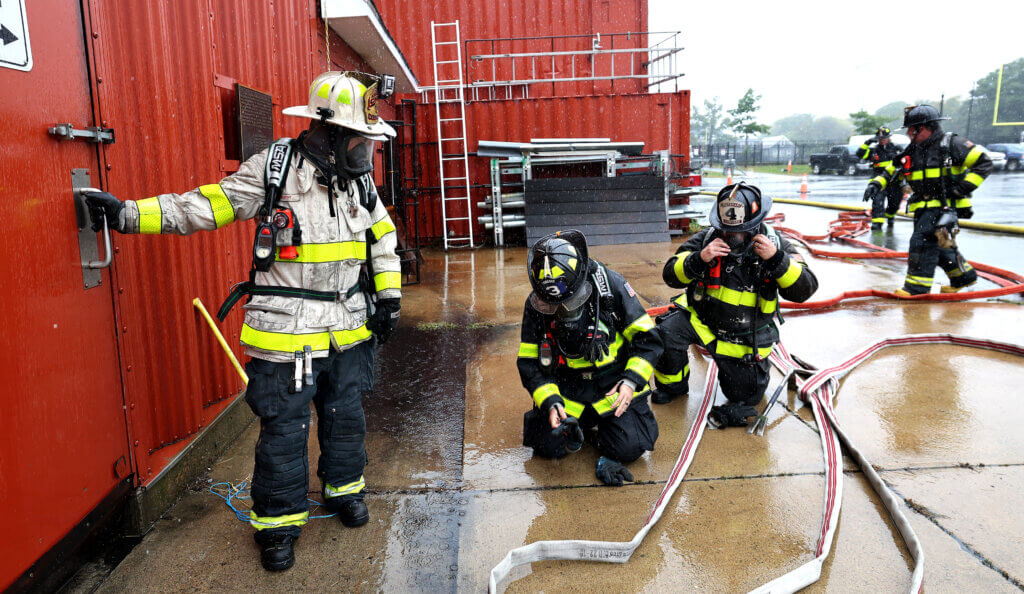 Acton Fire Department Assistant Chief Sean Murphy, left, prepares to open the door for to the Worcester Fire Department’s burn building during a “refresher” training session on Monday, September 27, 2026. This week was the first time Acton firefighers had trained at the Worcester facility. Ken McGagh/The Acton Bridge