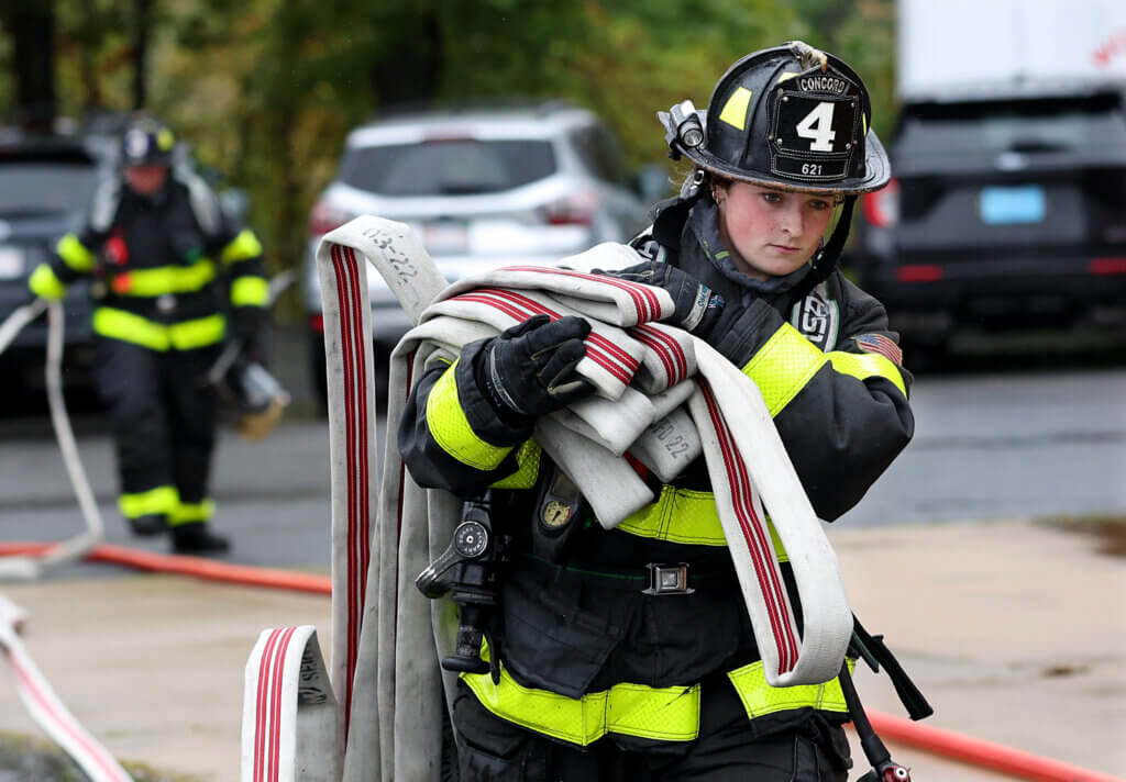 Acton firefighter Elsa Heil carries hose after one of five burn sessions at the Worcester Fire Department Training Center burn building on Monday, September 27, 2026. Ken McGagh/The Acton Bridge