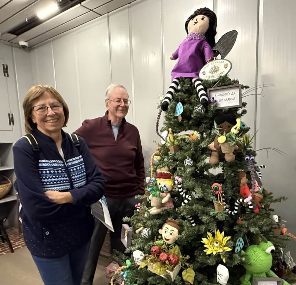 Concordians Peter and Mary Lowitt with the tree created by the West Acton Green Thumbs. “Millie Fleur’s Poison Garden,” by Christy Mandin, inspired the decorations. The book encourages readers to embrace what makes them different. Photo: Laurie O’Neill/The Acton Bridge