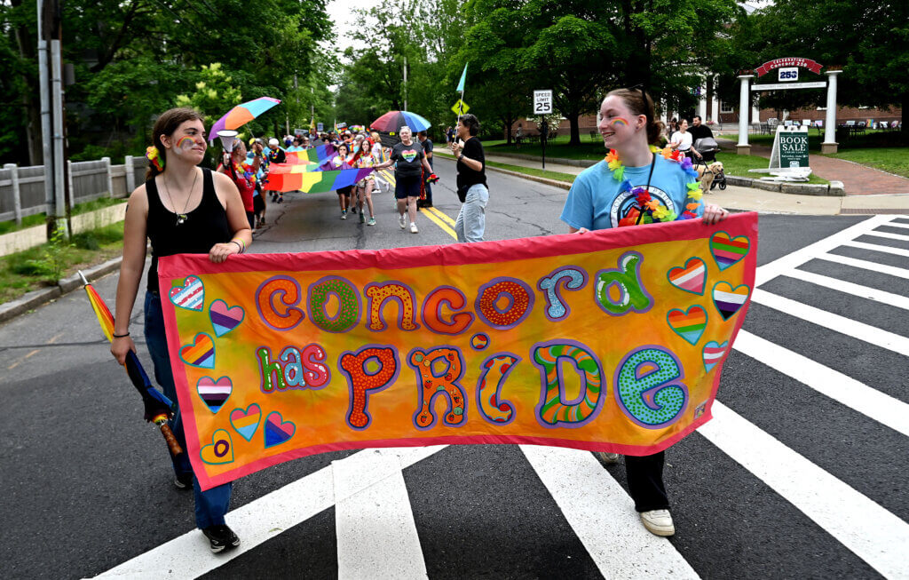 Parade participants carry a banner past the Acton Free Public Library.
