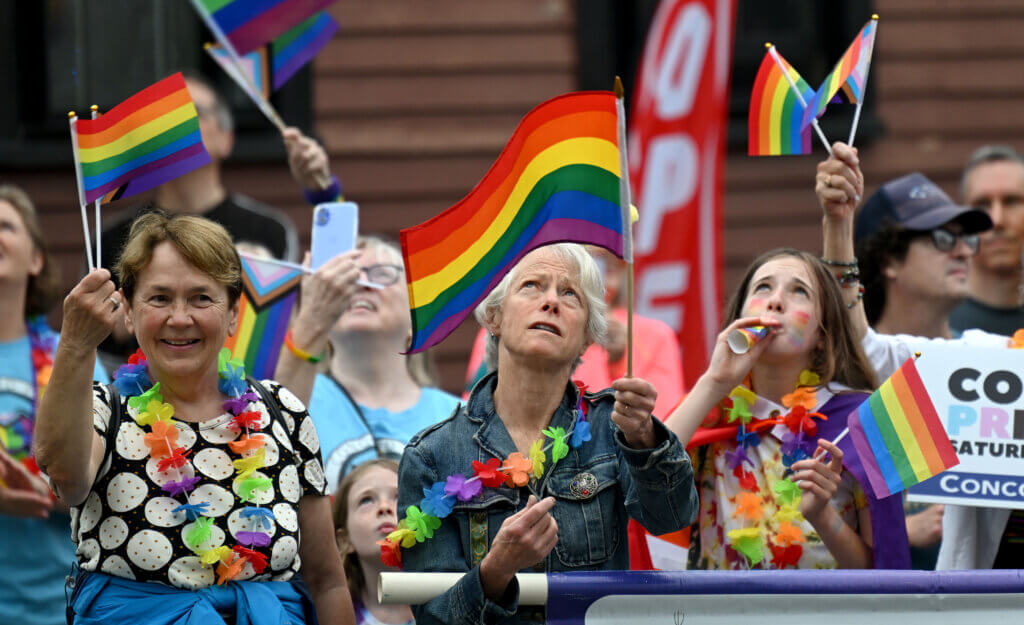 Spectators including Select Board member Mary Hartman, left, watch as the Pride flag is raised in Monument Square.
