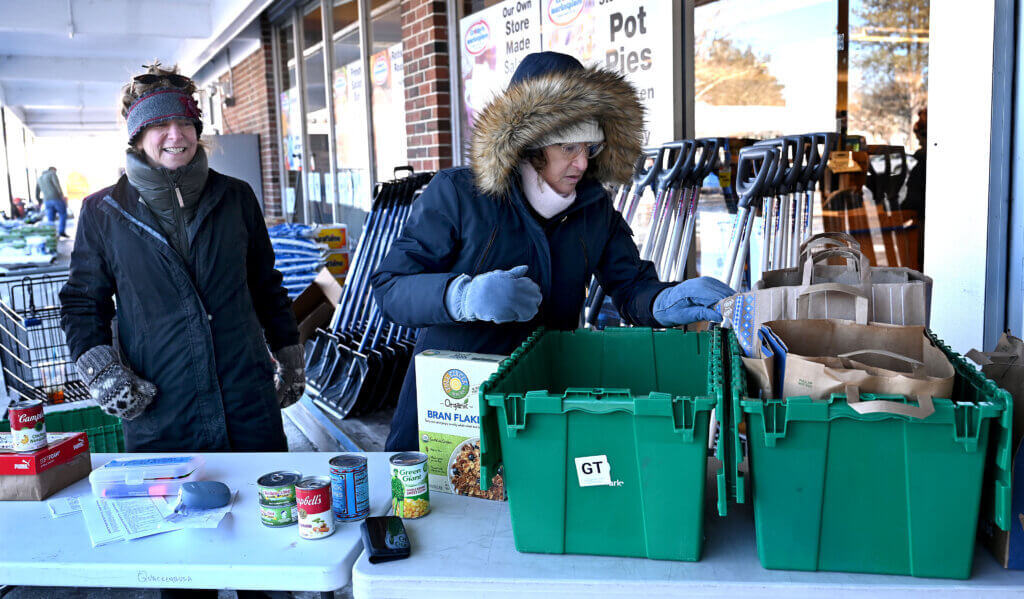 Sharon Brown, right, and Ronni Olitsky of the Acton-Carlisle Human Rights Council accept donations of food outside of Crosby’s Marketplace as part of a Martin Luther King Day of Service activity on Monday, January 20, 2024.   Ken McGagh/The Acton Bridge