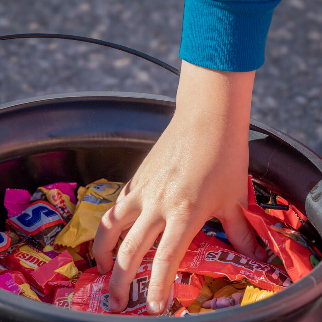 A hungry hand reaches into a witch’s cauldron for some M&Ms. Photo: Jean Fain/The Acton Bridge