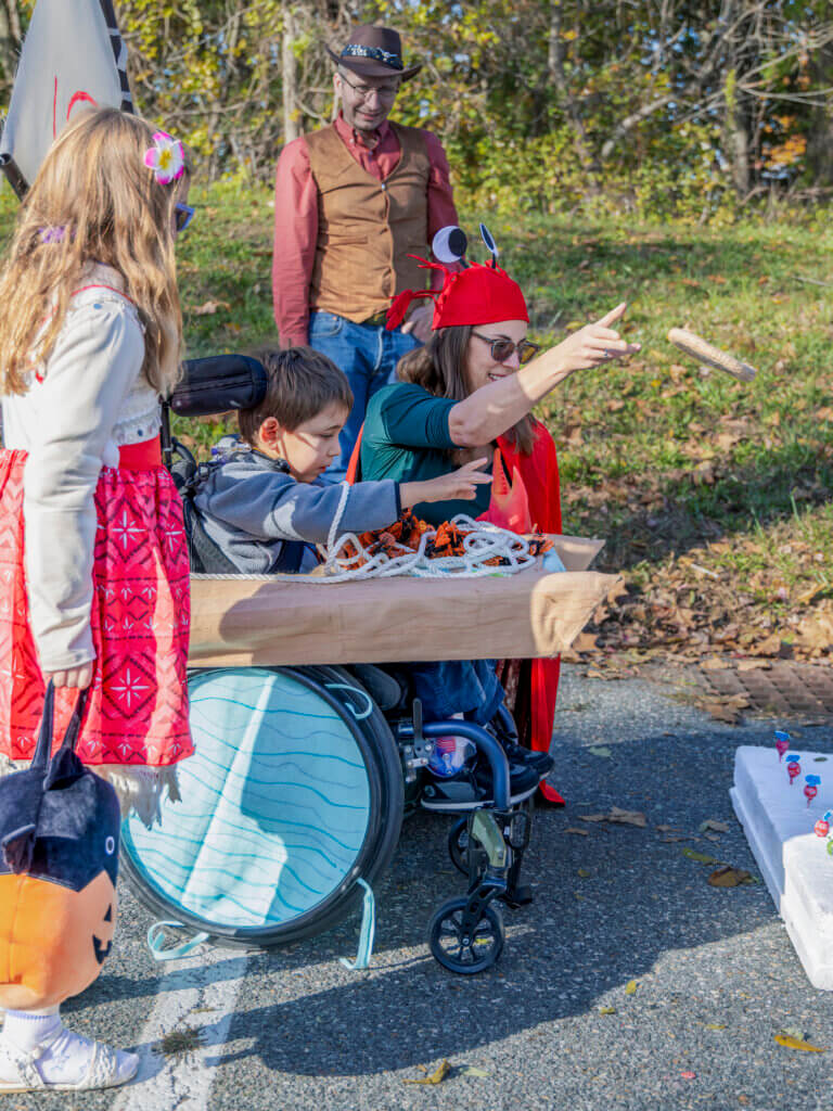 Laura Will helps son Alden, 5, at the Lollipop Ring Toss Game, as his sister Hadley, 7, stands by. Photo: Jean Fain/The Acton Bridge
