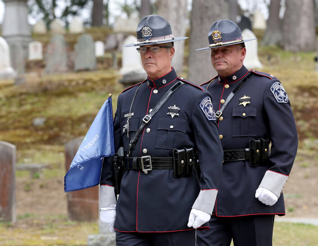 Middlesex Sheriffi’s Office Officer Joe Donlon, front and Assistant Deputy Superintendent John Panaggio march as they carry a flag to place at the grave of Jail Master David S. Robinson of Acton at Sleepy Hollow Cemetery in Acton on Wednesday, April 29, 2026. Ken McGagh/The Acton Bridge